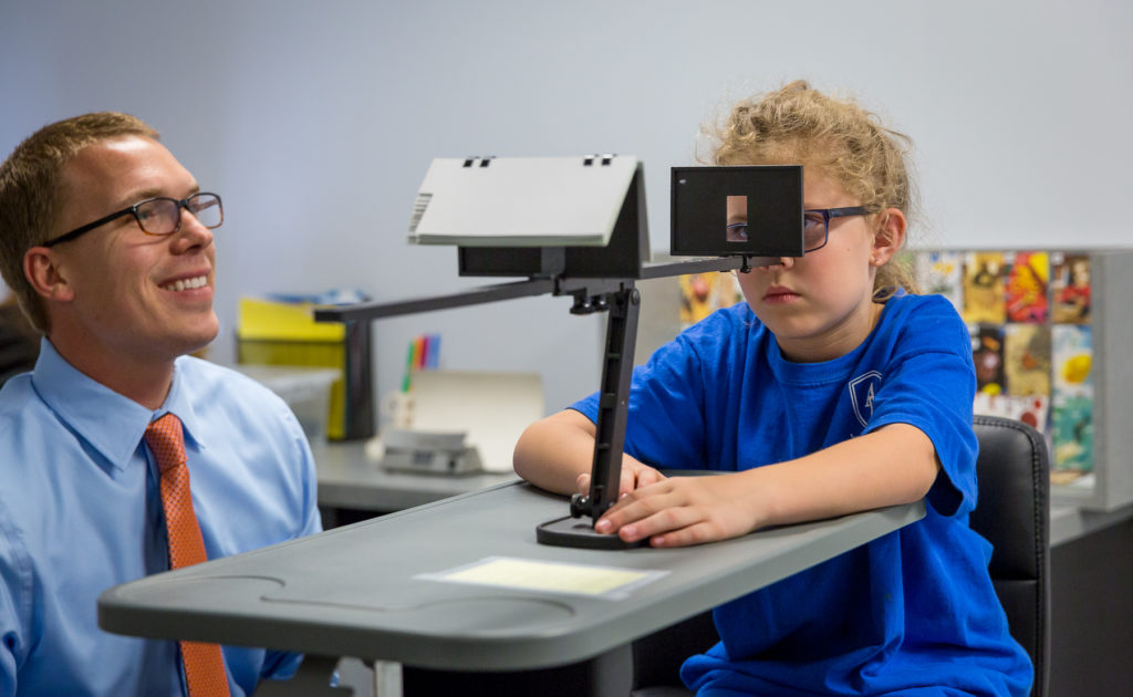 A Walesby Vision Center doctor working one-on-one with a young patient